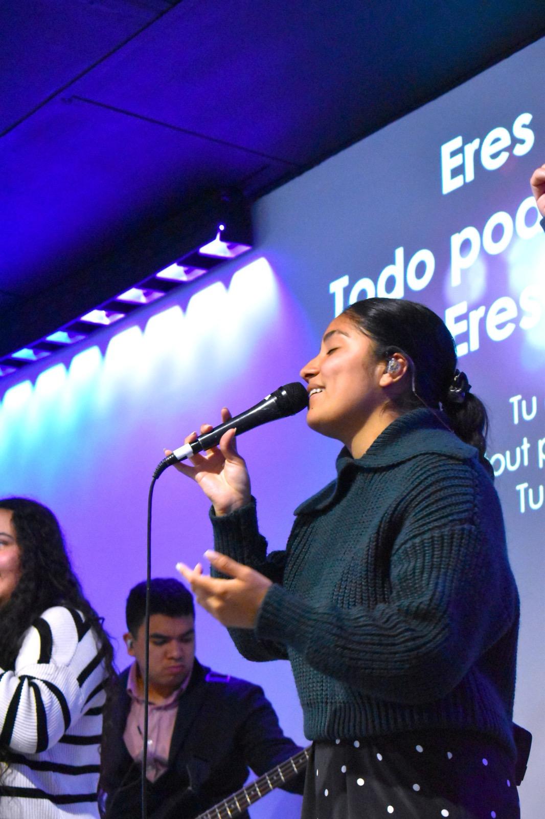 Une chanteuse de l’équipe de louange chante, les yeux fermés